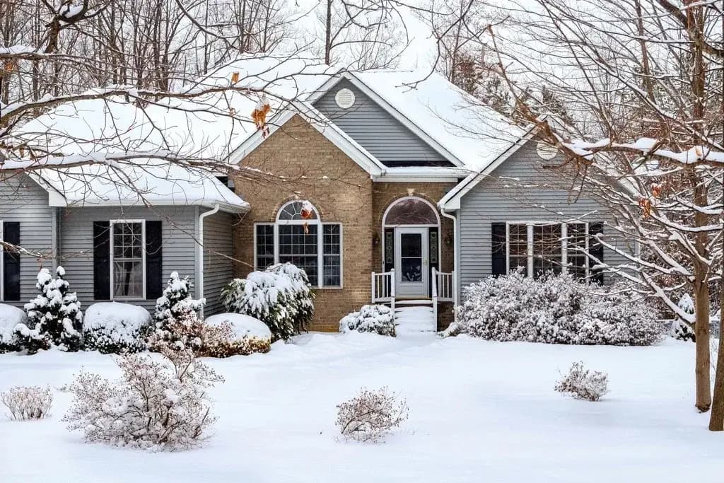 Snow-covered single-story house on a winter day, the kind of cold climate home a DIY mini split heat pump has to keep warm