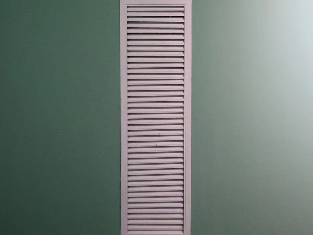 White supply grille set into a mint green wall, the only visible part of a concealed duct mini split multi zone install